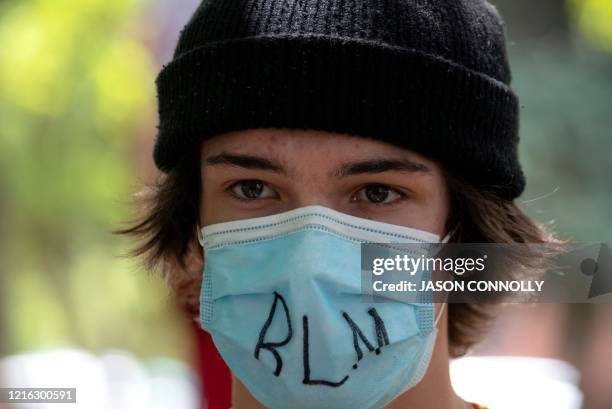 Protestor wears a face mask with the initials of the Black Lives Matter movement written on it in Denver, Colorado on May 30, 2020 while protesting...