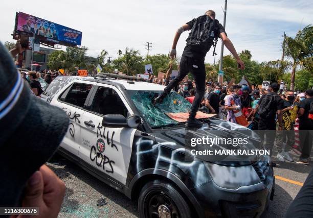 Demonstrators smash a police vehicle in the Fairfax District as they protest the death of George Floyd, in Los Angeles, California on May 30, 2020. -...