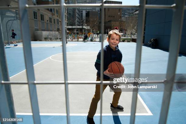 Boy plays basketball at a public playground on 1st avenue as New York City attempts to slow down the spread of coronavirus through social distancing...