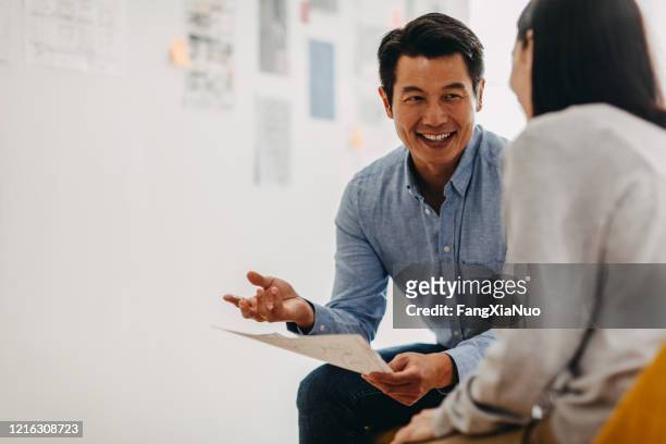 korean graphic designer sharing ideas during meeting in modern office studio - interview event stock pictures, royalty-free photos & images