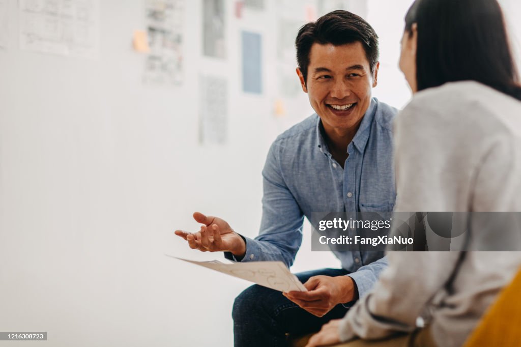 Korean graphic designer sharing ideas during meeting in modern office studio