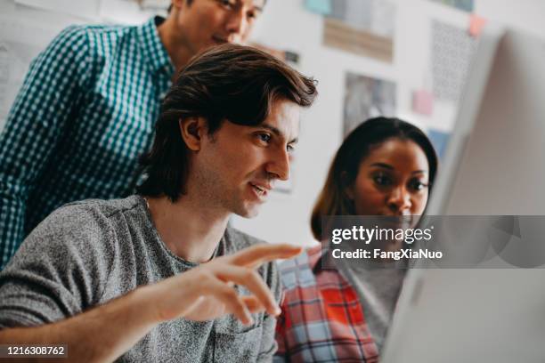 group of architects looking at computer screen discussing ideas in office studio - user experience stock pictures, royalty-free photos & images