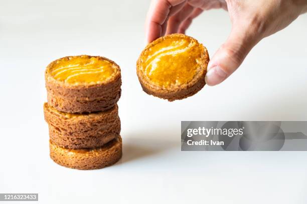 womans hand holding a homemade cookies, bretagne sables, galette bretonne, with stacked tower and white background - biscotte stock-fotos und bilder