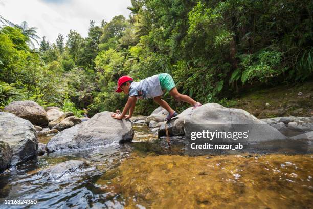 kid hiking through rocks next to stream. - new zealand forest stock pictures, royalty-free photos & images