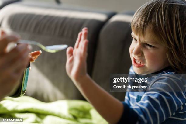 boos weinig jongen die medische stroop thuis weigert te drinken. - weigeren stockfoto's en -beelden