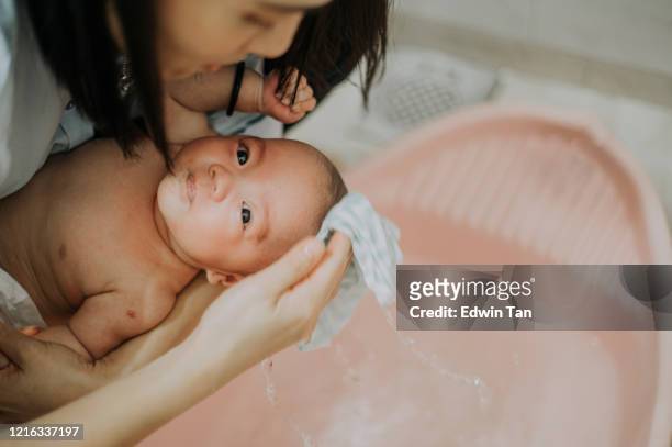 una madre china asiática tomando el baño para su bebé en el baño - bañando bebe fotografías e imágenes de stock