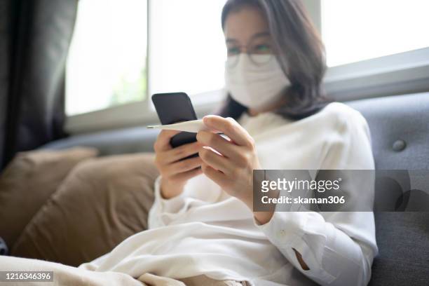 asian female use thermometer checking temperature for fever or covid-19 (corona virus) and  coronavirus outbreak 14 day at home - digital thermometer stock pictures, royalty-free photos & images