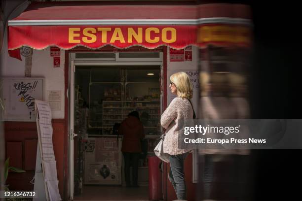 Woman queues at a tobacconist, open as it is an essential service allowed to sell to the public despite the confinement measures of the state of...