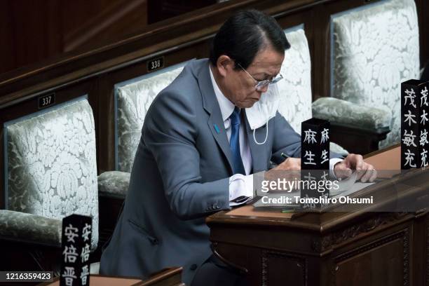 Japan's Deputy Prime Minister and Finance Minister Taro Aso wearing a face mask attends an ordinary session at the upper house of parliament on April...