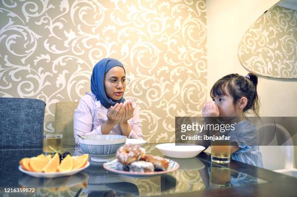 young asian daughter eating with mother in the kitchen - fasting stock pictures, royalty-free photos & images