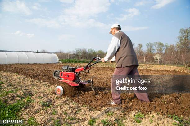 el hombre cultiva la tierra - harrow fotografías e imágenes de stock