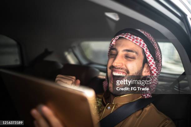 arab middle east man watching sports using digital tablet inside a car - qatar man stock pictures, royalty-free photos & images