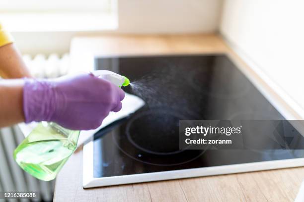 handen in handschoenen die ceramisbovenkant voor desinfectie bespuiten - burner stove top stockfoto's en -beelden