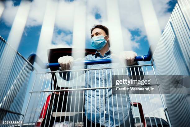 woman with empty shopping cart wearing protective surgical masks and gloves - store opening covid stock pictures, royalty-free photos & images