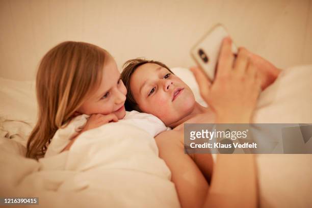 brother and sister using smart phone in bed - preteen girl no shirt stock pictures, royalty-free photos & images