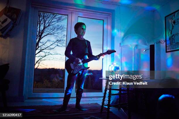 boy playing electric guitar in living room with neon light - kids room stock pictures, royalty-free photos & images
