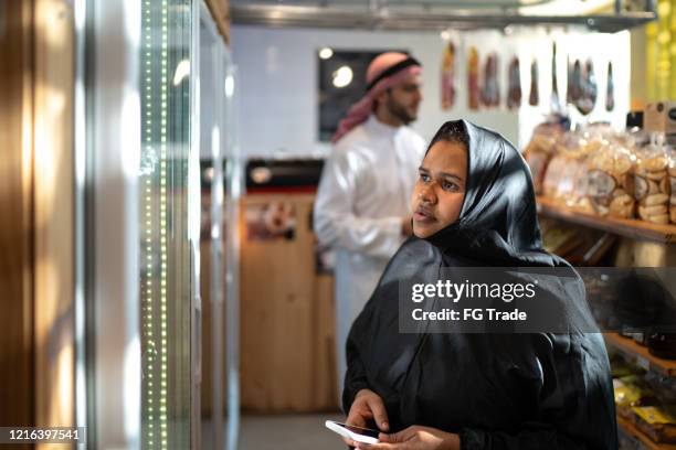 arab middle east woman buying with mobile phone at convenience store - arab shopping stock pictures, royalty-free photos & images