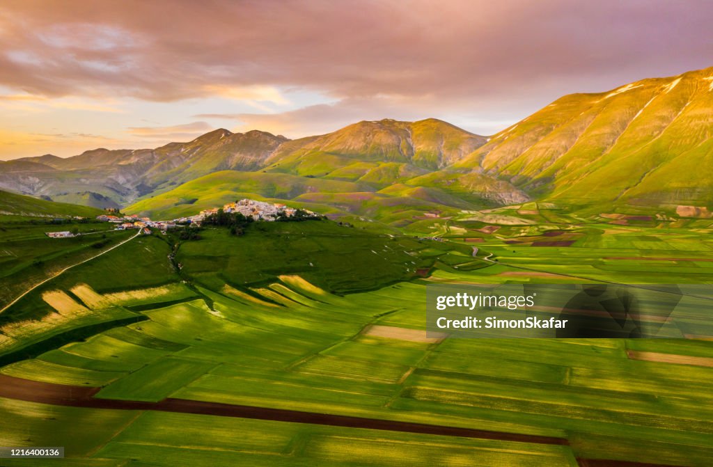 Vista aérea panorámica de un paisaje rural con un montón de campos de patchwork y hermosas colinas verdes onduladas, Castelluccio, Umbría, Italia