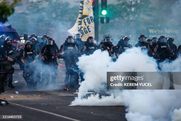 Smoke rises near a row of police in riot gear near the 5th police precinct during a demonstration to call for justice for George Floyd, a black man...