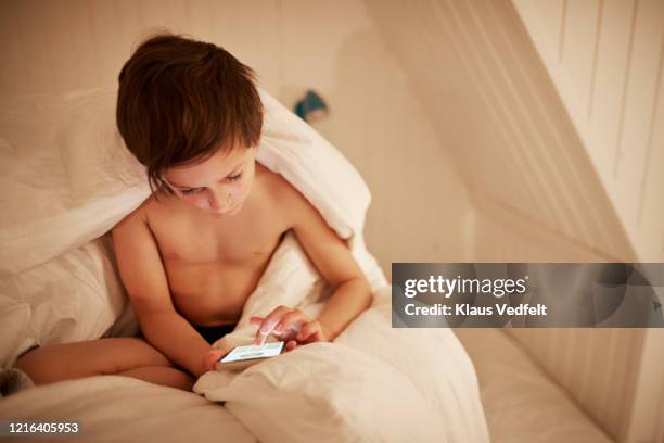 boy using smart phone in bed - sin camisa fotografías e imágenes de stock