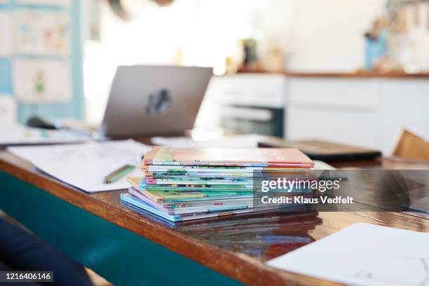 school books stacked on dining table - text book stockfoto's en -beelden