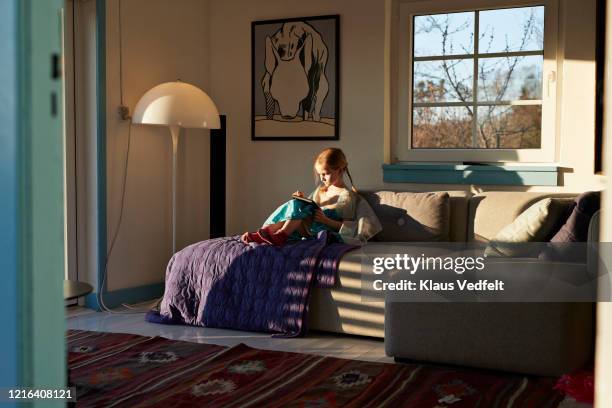 girl using digital tablet on sunny living room sofa - girl without a room stock pictures, royalty-free photos & images