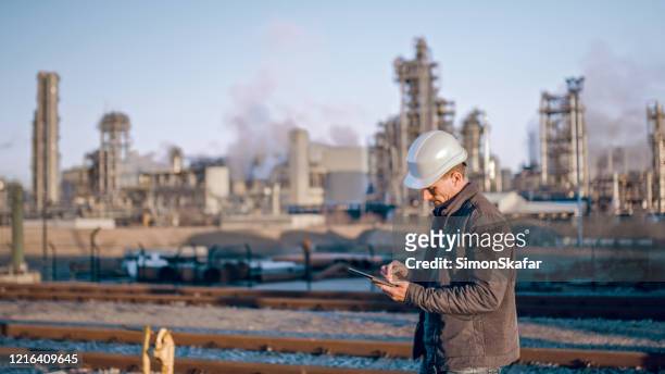 engineer using tablet near oil refinery industry. - oil refinery stock pictures, royalty-free photos & images