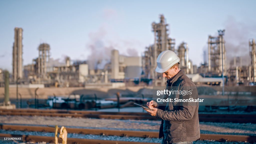 Engineer using tablet near oil refinery industry.