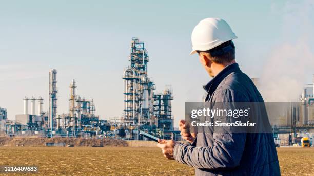 ingenieur die tablet dichtbij olieraffinaderij gebruikt. - gas engineer stockfoto's en -beelden