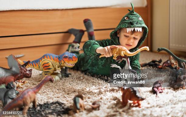 cute boy playing with his dinosaurs - costume players stock pictures, royalty-free photos & images