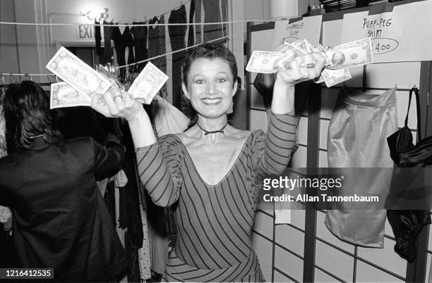 Portrait of American fashion designer Betsey Johnson, her hands full of money, as she poses in her studio during a public sale, New York, New York,...