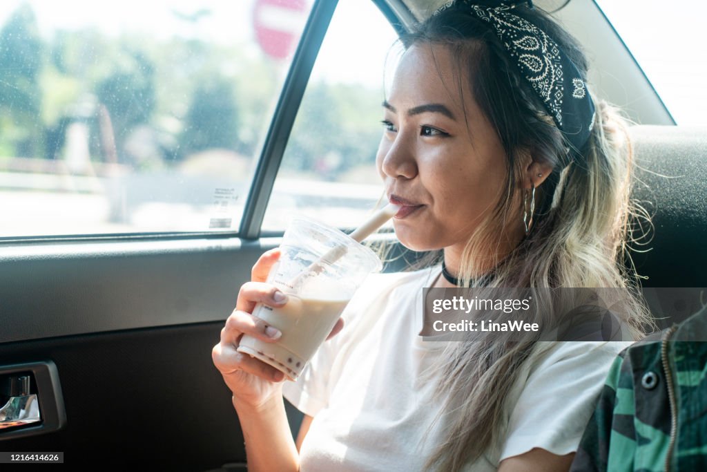Young millennial drinking bubble tea in the car