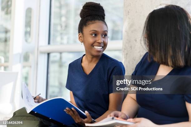 young adult woman quizzes friend on notes - community college campus stock pictures, royalty-free photos & images