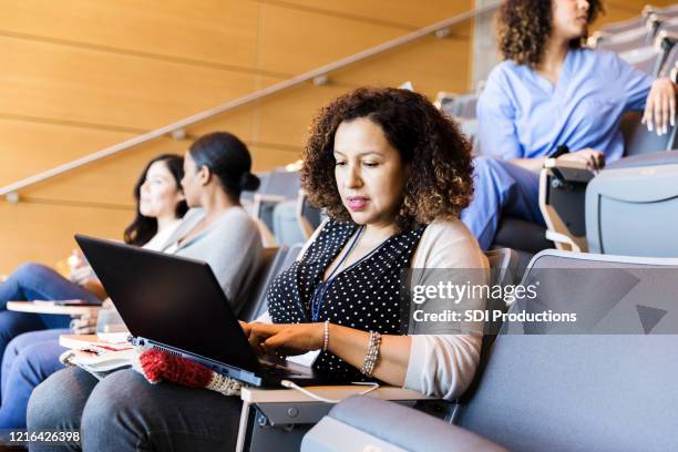 mid adult female student catches up on notes before class - community college stock pictures, royalty-free photos & images