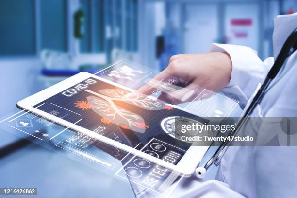 doctor analyzing covid-19 or coronavirus test result with futuristic tablet - coronavirus doctor stock pictures, royalty-free photos & images