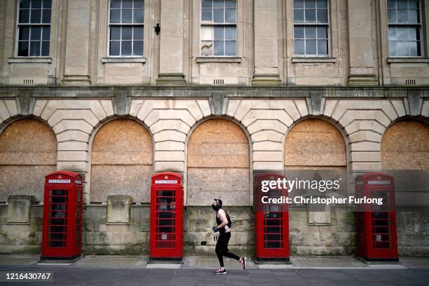 Man wearing a mask jogs past red phone boxes in Blackpool town centre as people and businesses observe the pandemic lockdown and stay home on April...