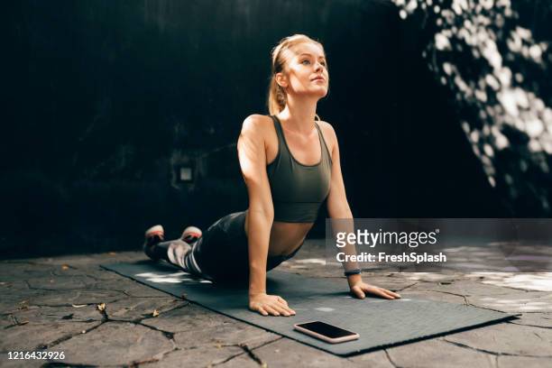 allenarsi con un'app fitness: adatta donna bionda che fa yoga all'aperto - blonde yoga foto e immagini stock