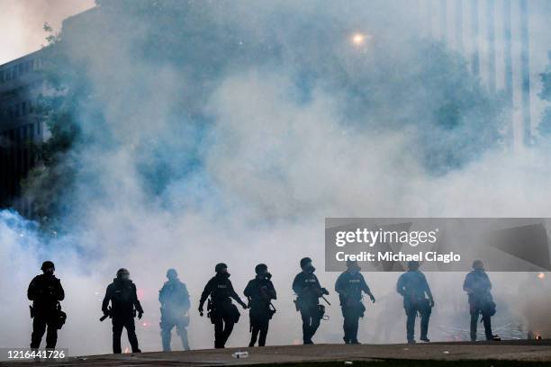 Police officers walk through a cloud of tear gas as they try to disperse people protesting against the death of George Floyd in front of the Colorado...