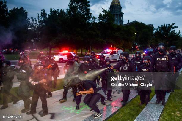 Police officers pepper spray a woman next to the Colorado State Capitol as protests against the death of George Floyd continue for a third night on...