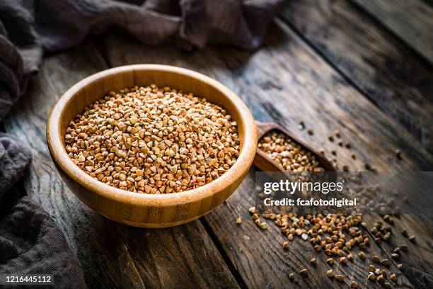 dietary fiber: wholegrain buckwheat in a wooden bowl on rustic kitchen table - buckwheat stock pictures, royalty-free photos & images