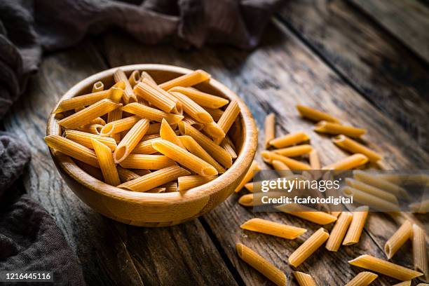 wholegrain pasta on rustic wooden table - penne imagens e fotografias de stock