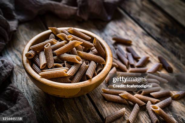 volkorenpasta op rustieke houten lijst - volkorentarwe stockfoto's en -beelden