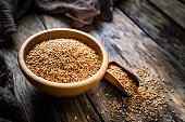 Healthy food: flax seeds in a bowl shot on rustic wooden table