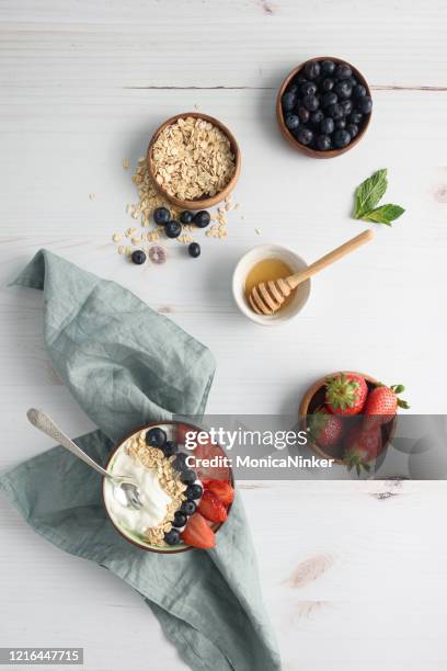 bowl of yogurt with berries and oatmeal on table - snack bowl stock pictures, royalty-free photos & images