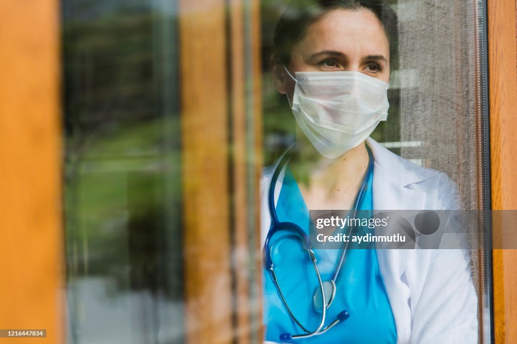 Female doctor looking through window at hospital
