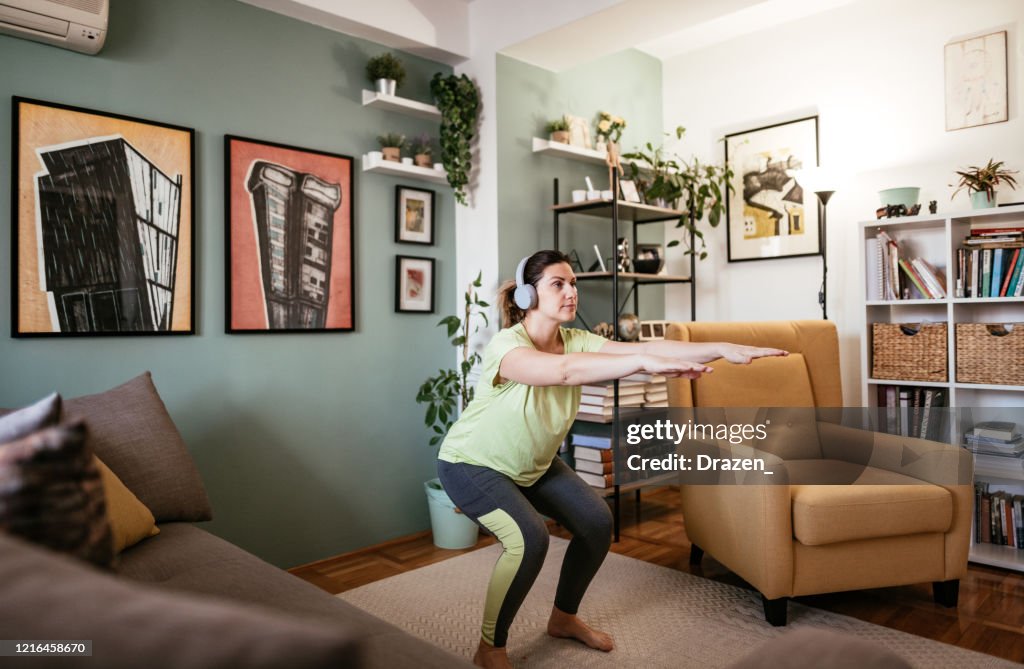 Adult woman exercising at home during quarantine - crouching and strength exercises