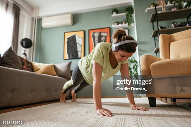 adult woman exercising at home during quarantine, doing push ups - press ups stock pictures, royalty-free photos & images