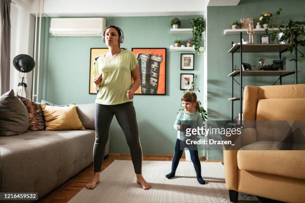 femme adulte dansant à la maison pendant la quarantaine avec la fille de trois ans - salle yoga photos et images de collection