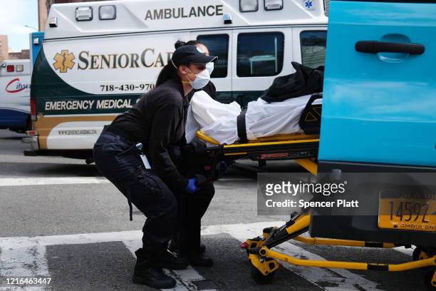 Two health workers lift a patient in to a hospital at Mount Sinai Beth Israel hospital on April 02, 2020 in New York City. Hospitals in New York...