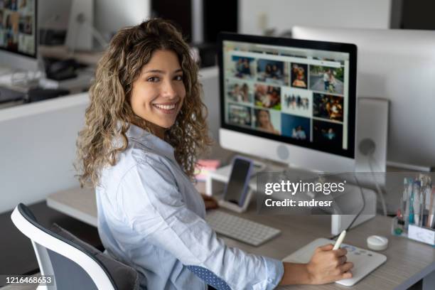 mujer feliz editando imágenes en una oficina creativa - deitar fotografías e imágenes de stock